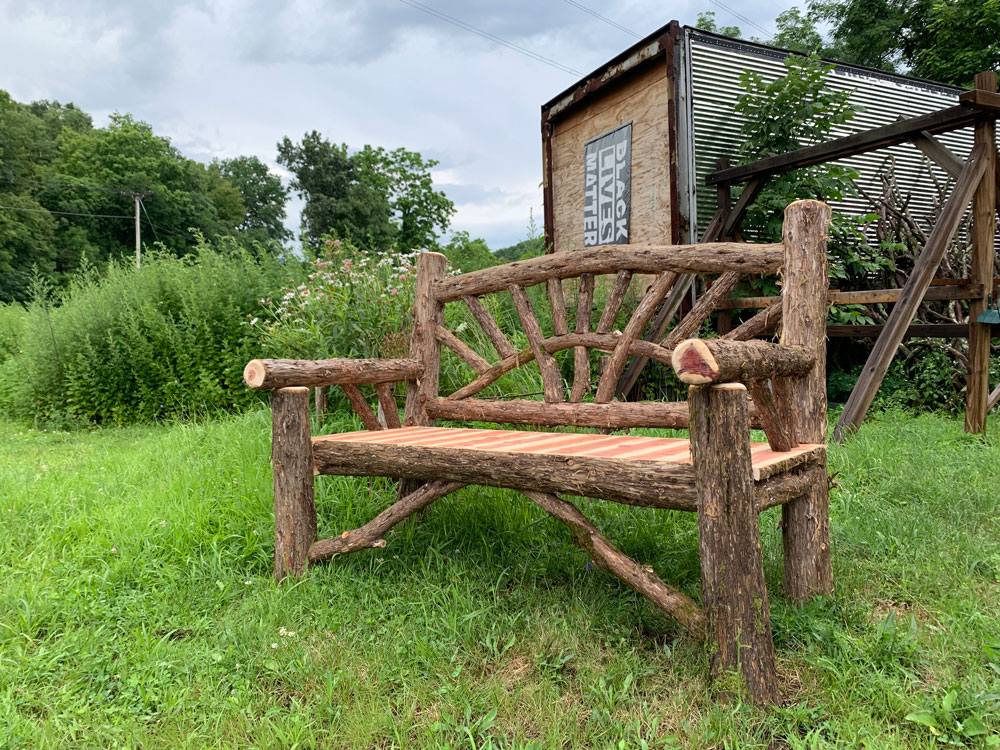Outdoor rustic garden bench built using bark-on trees and branches titled the Waterloo Bench