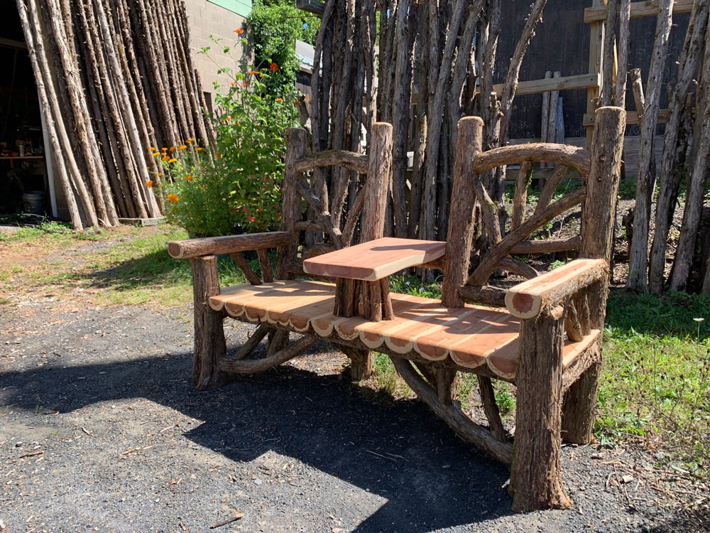 Rustic bench custom built using cedar trees and branches titled the Couple's Bench