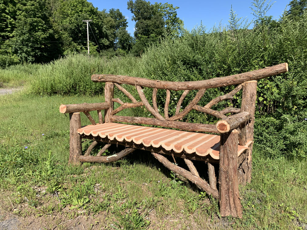 Outdoor park bench built in the rustic style using logs and branches titled theFalling Water Bench