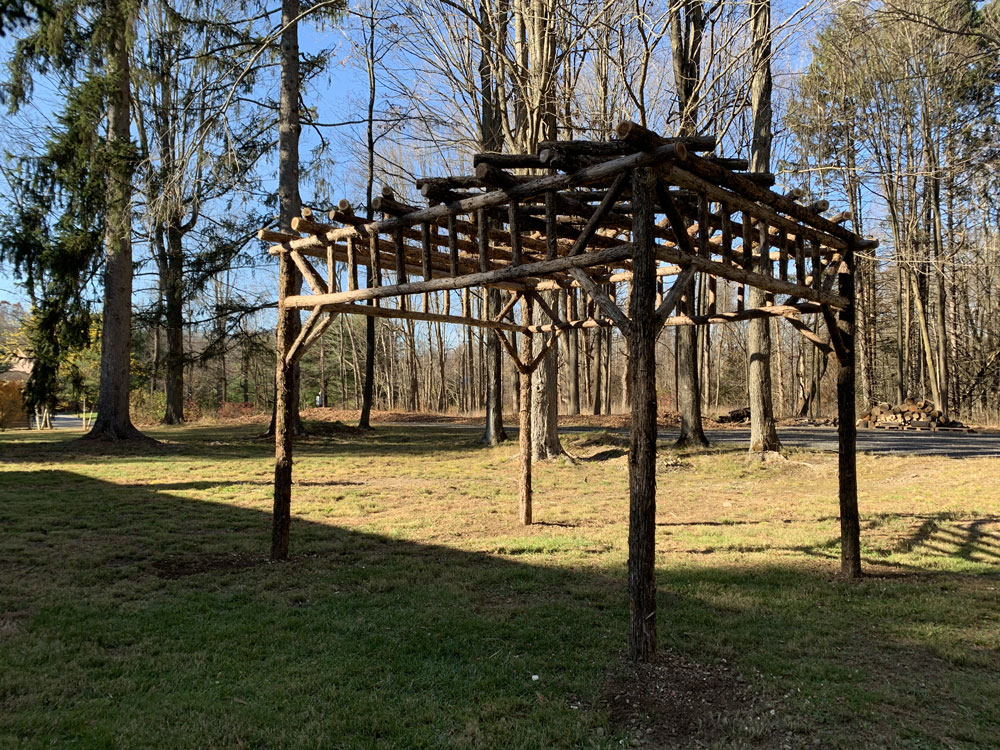 Rustic natural pergola made from bark-on cedar logs, twigs, and branches titled the Staatsburg Pergola