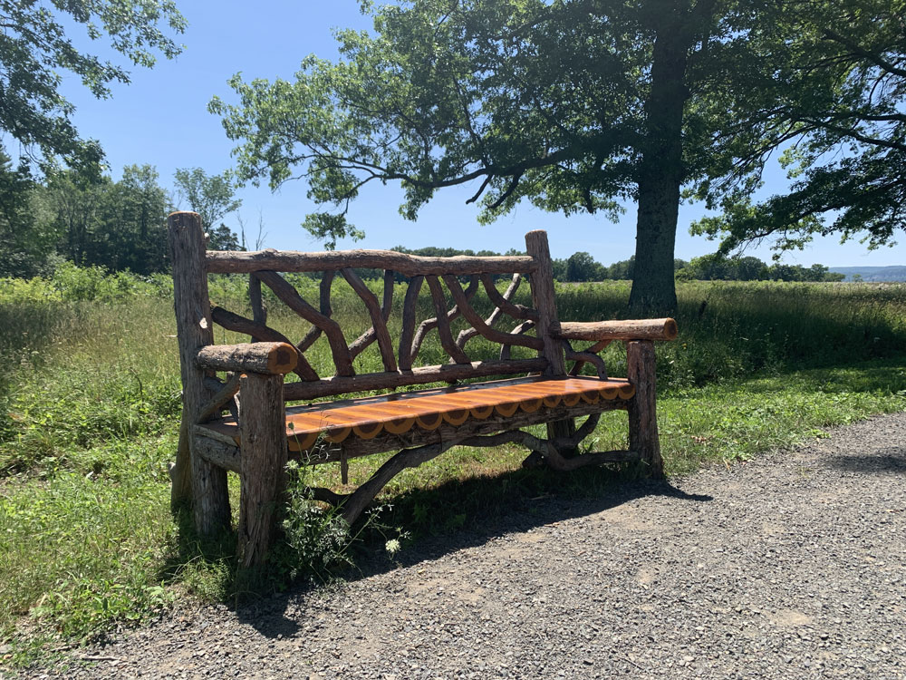 Outdoor park bench built in the rustic style using logs and branches titled the Mohonk Bench