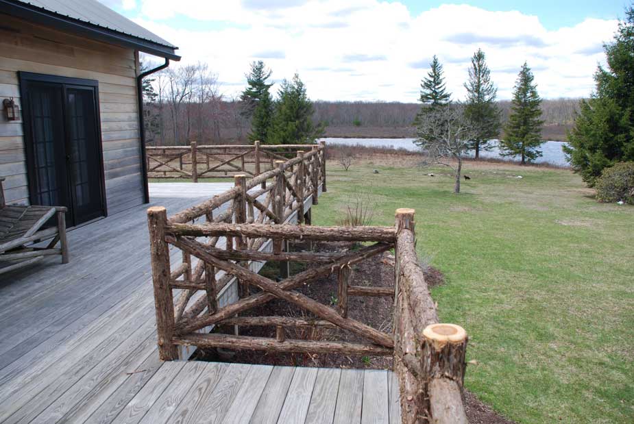 Rustic railings built using bark-on trees and branches titled the Huguenot Deck Railings