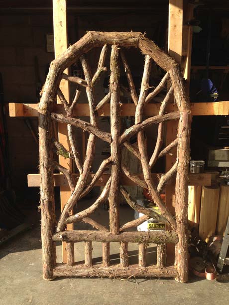 Rustic gates built using bark-on trees and branches titled the Beam Gates