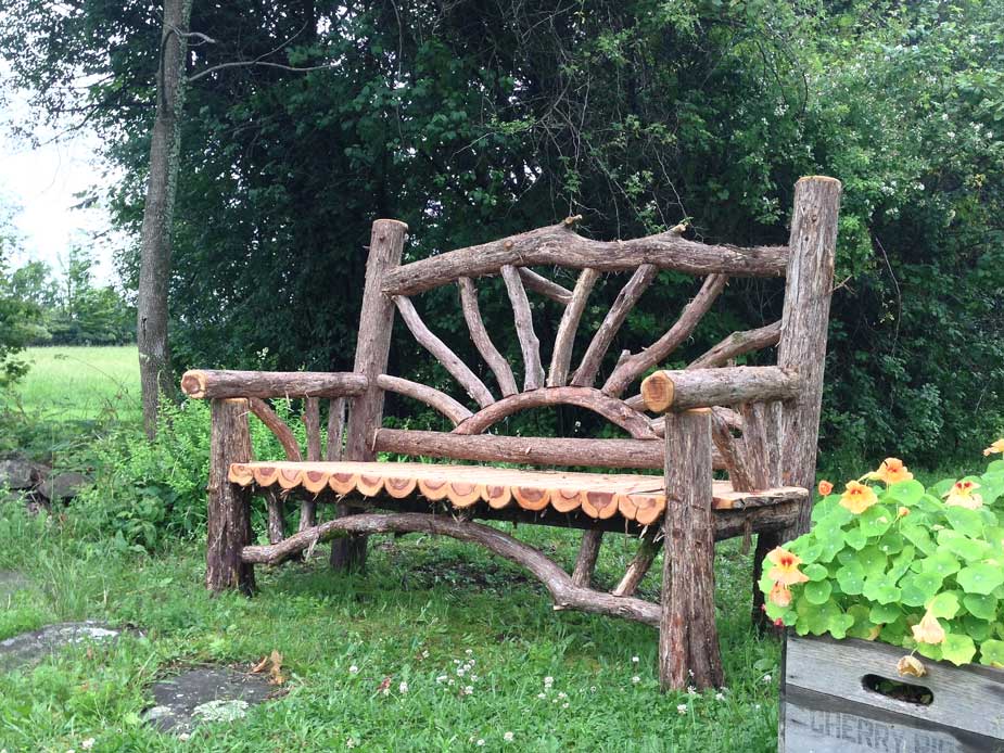 Rustic bench custom built using cedar trees and branches titled the Sunburst Bench