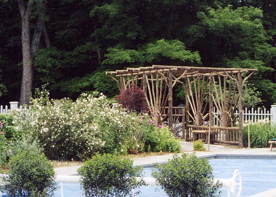 Rustic garden pergola built using bark-on trees and branches titled the Sunburst