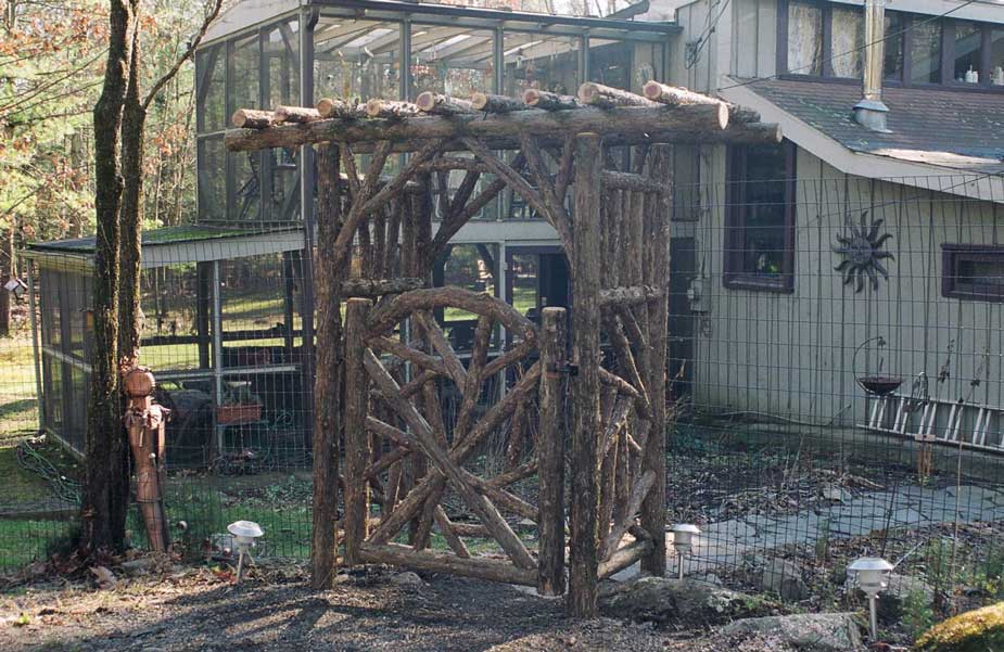 Rustic garden arbor and gate built using bark-on trees and branches titled the Woodstock