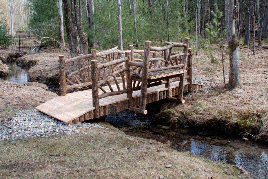 Bridge with built in bench in the rustic style using logs and branches titled the Belluck Bridge