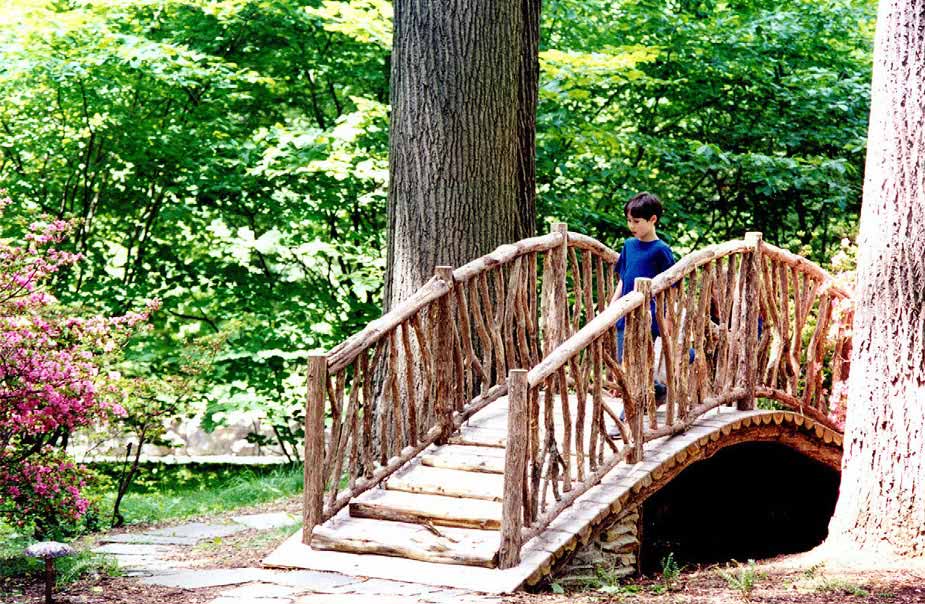 Rustic bridge custom built using cedar trees and branches titled Winterthur Troll Bridge
