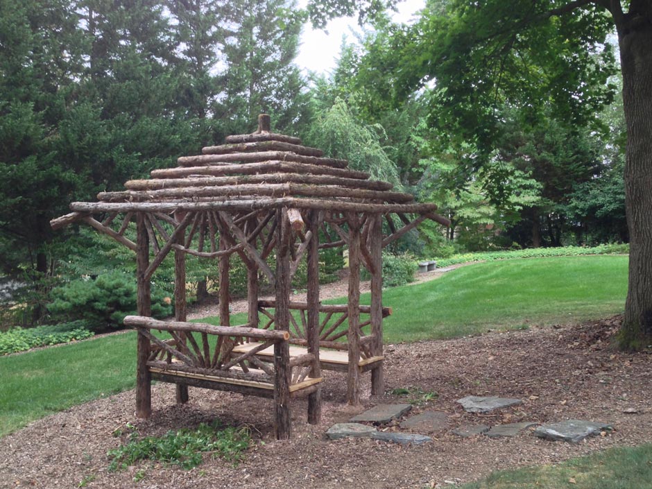 Rustic garden strucutre built using bark-on trees and branches titled the Briarcliffe Shelter