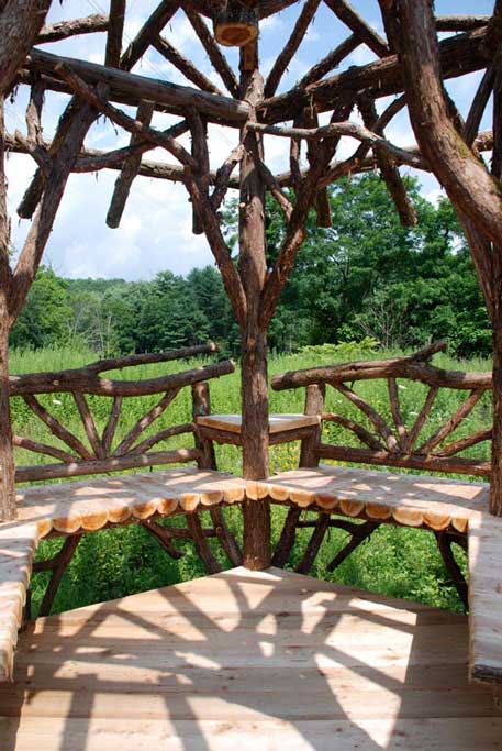 A detail of the interior of a rustic garden structure built using bark-on trees and branches titled the Unger House