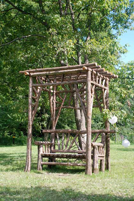 Rustic garden covered bench built using bark-on eastern red cedar trees and branches