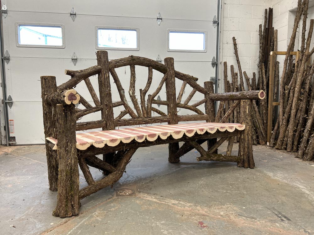 Outdoor rustic garden bench built using bark-on trees and branches titled the Poet's